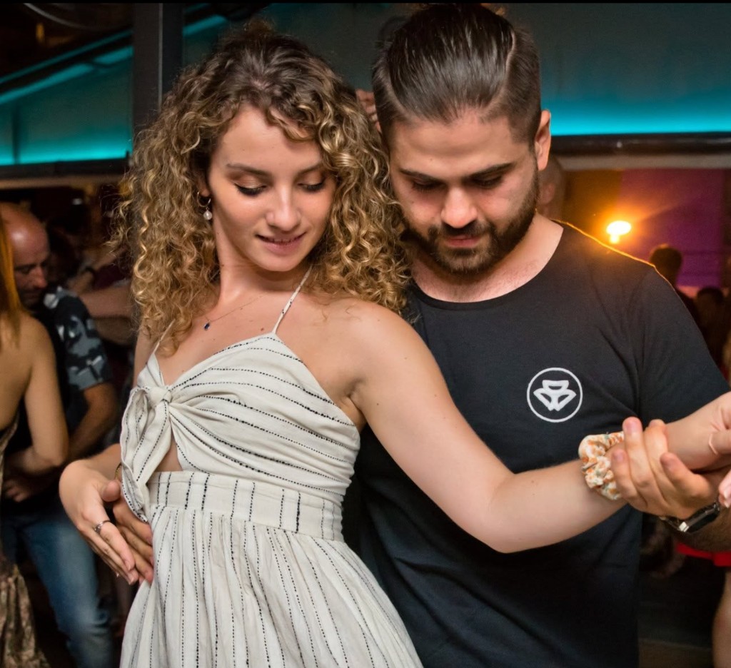 A couple dancing bachata in close connection on a social dance floor